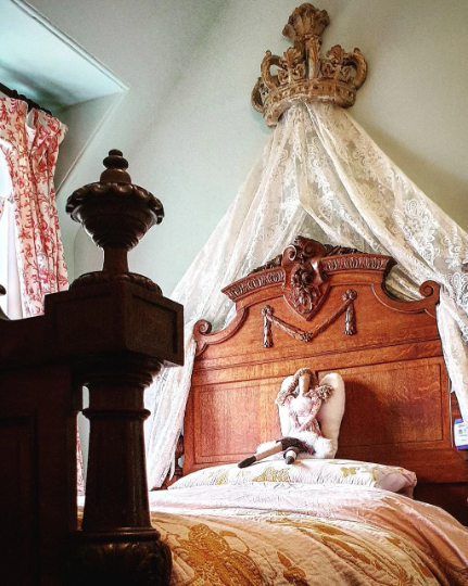 Photogrpah of a vintage bed with a crown and and curtain drape above it